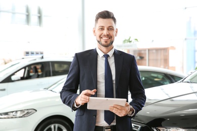 Salesman with tablet in salon. Buying new car