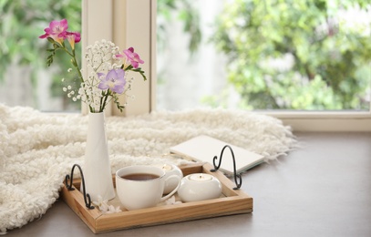 Beautiful fresh flowers and hot coffee on window sill indoors