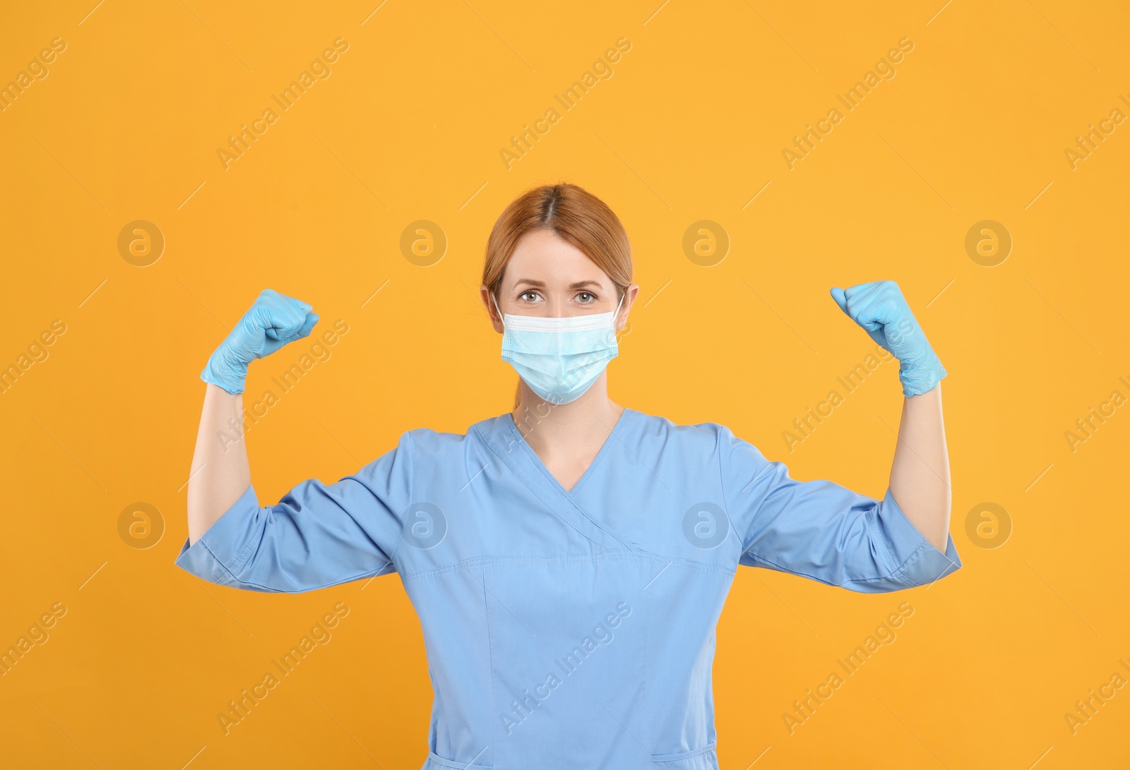Photo of Doctor with protective mask showing muscles on yellow background. Strong immunity concept