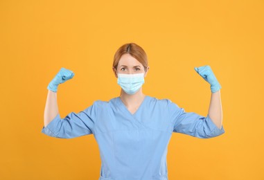 Doctor with protective mask showing muscles on yellow background. Strong immunity concept