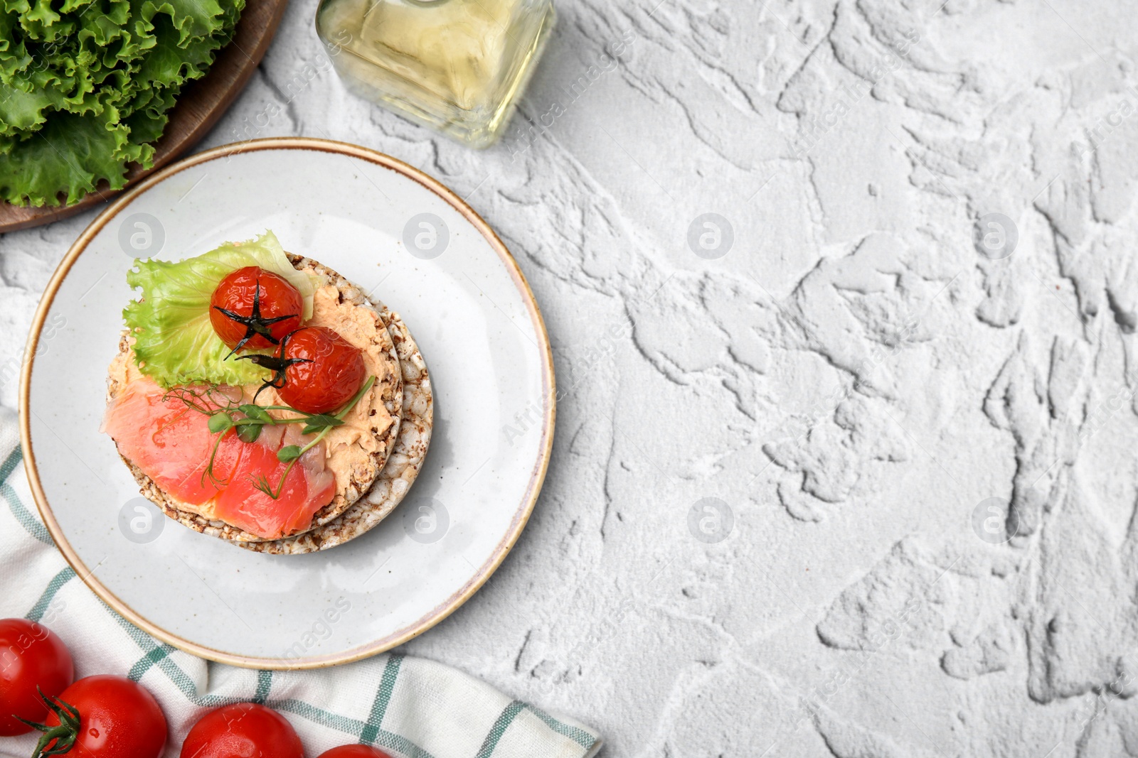 Photo of Crunchy buckwheat cakes with salmon, tomatoes and greens on white table, flat lay. Space for text