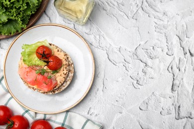 Crunchy buckwheat cakes with salmon, tomatoes and greens on white table, flat lay. Space for text