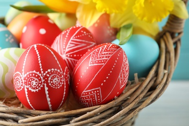 Photo of Painted Easter eggs in wicker basket, closeup