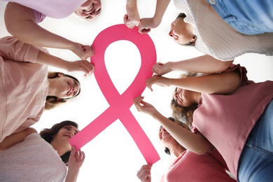 Photo of Women holding pink paper ribbon, bottom view. Breast cancer awareness concept