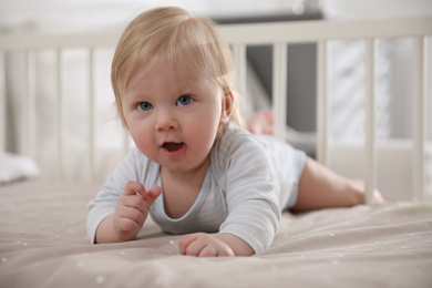 Photo of Adorable little baby lying in comfortable crib