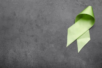 World Mental Health Day. Green ribbon on black background, top view with space for text