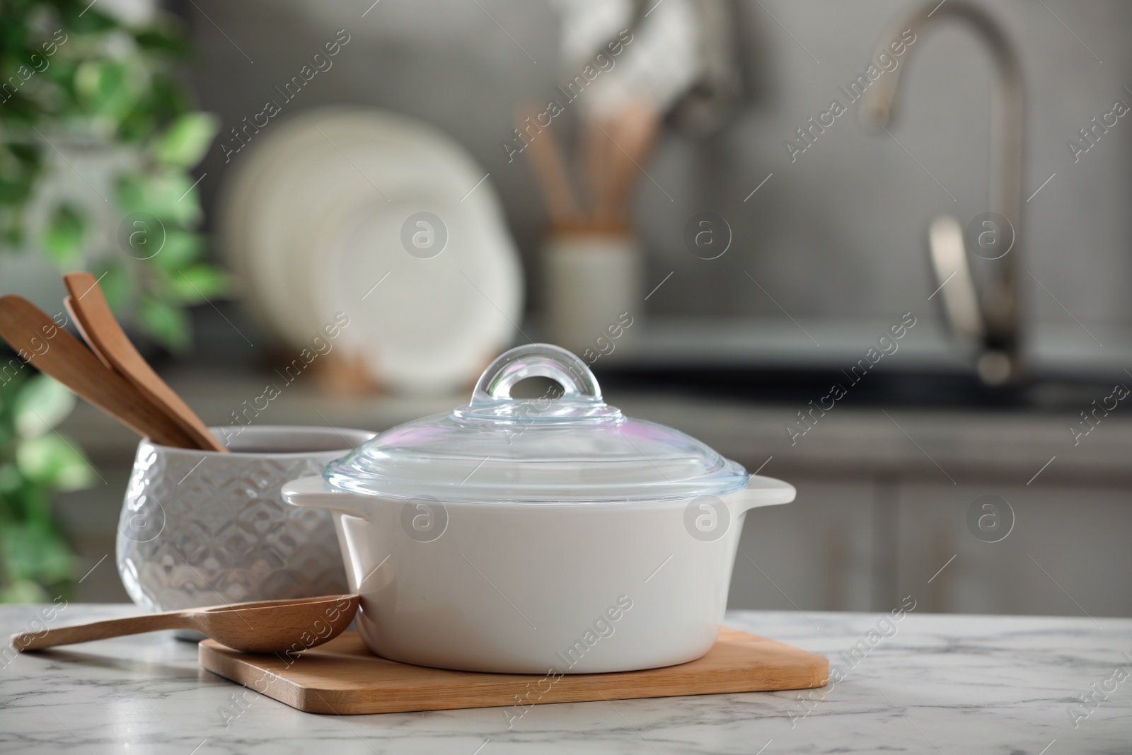 Photo of Ceramic pots and cooking utensils on white marble table in kitchen