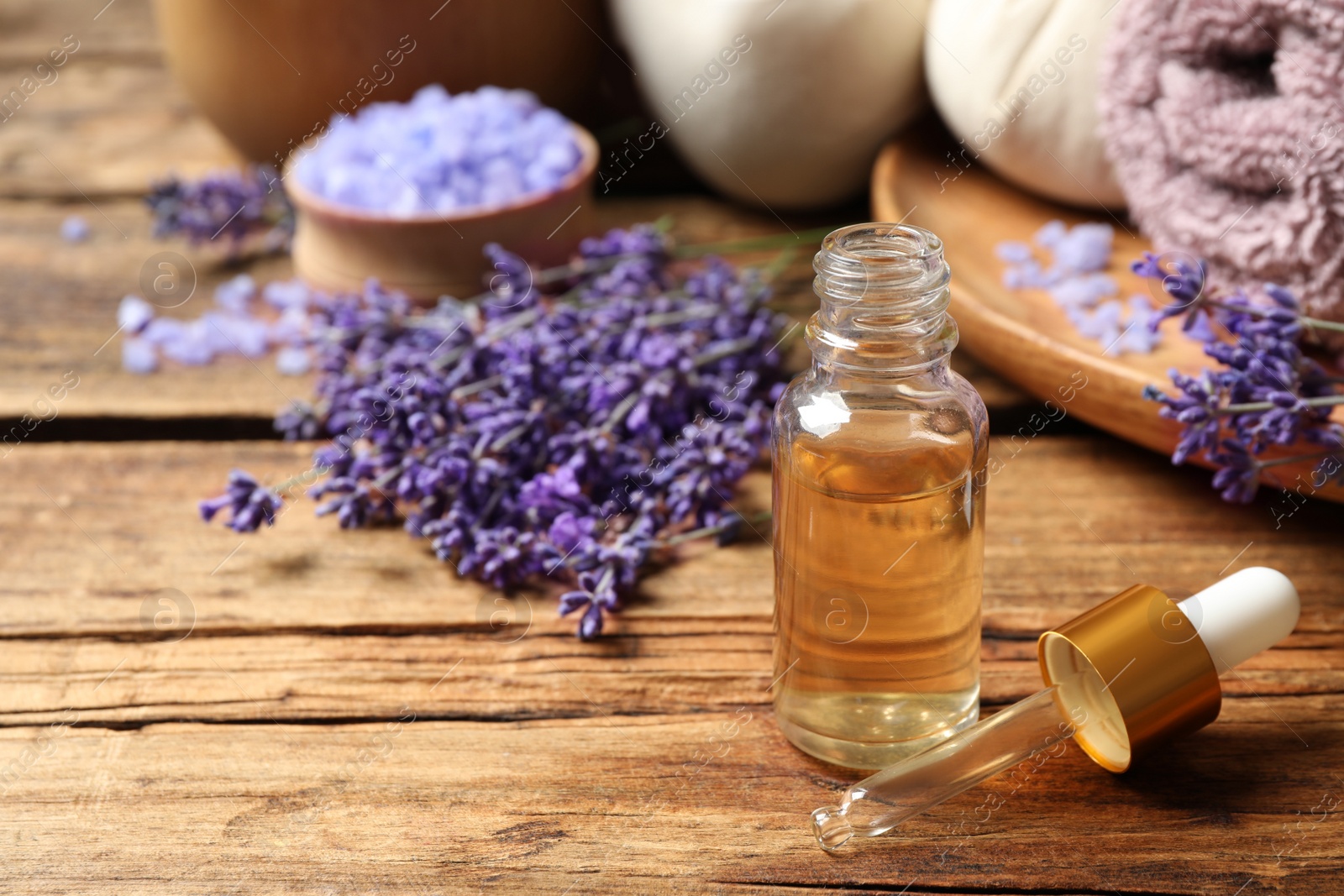 Photo of Composition with essential oil and lavender flowers on wooden table. Space for text