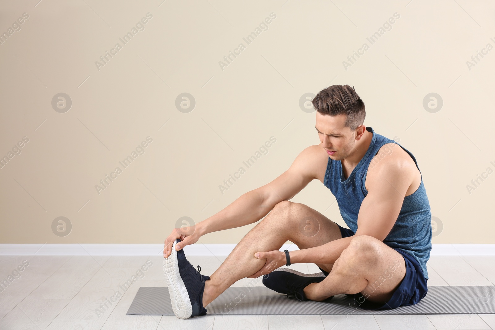 Photo of Male athlete suffering from leg pain during training indoors