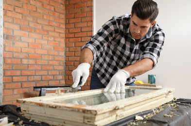 Photo of Man repairing old damaged window at table indoors