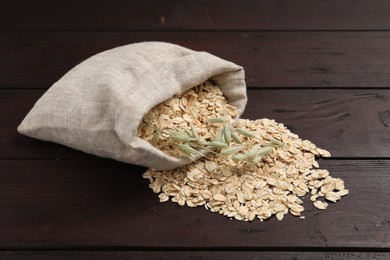 Photo of Overturned sack with oatmeal and florets on dark wooden table