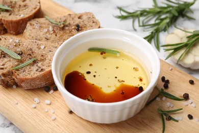 Photo of Bowl of organic balsamic vinegar with oil, bread slices and spices on white table, closeup