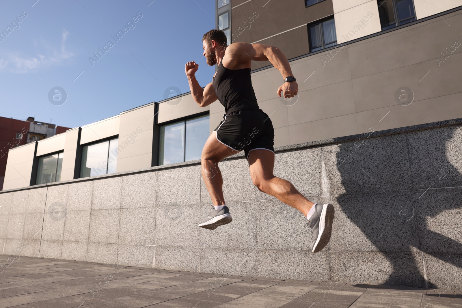 Photo of Young man running near building outdoors, low angle view. Space for text
