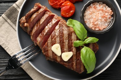 Delicious grilled beef steak served with spices and tomatoes on table, top view