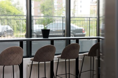 Photo of Table and bar stools near window in hostel dining room