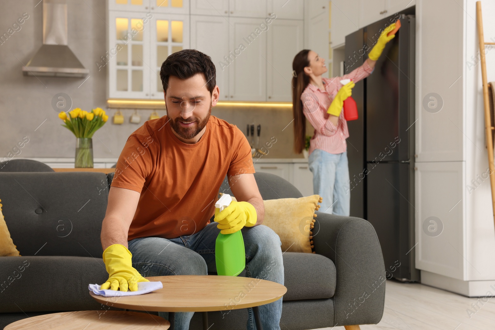 Photo of Spring cleaning. Lovely couple tidying up living room and kitchen together