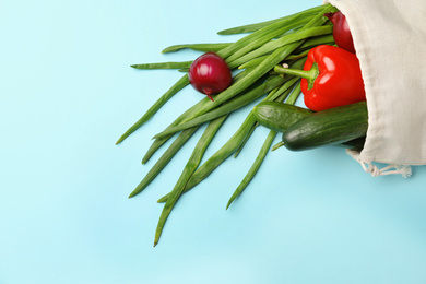 Photo of Cotton eco bag with vegetables on light blue background, top view