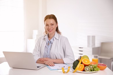 Image of Nutritionist with clipboard and laptop at desk in office
