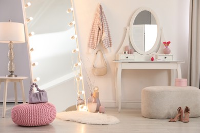 Large mirror with light bulbs and dressing table in stylish room. Interior design