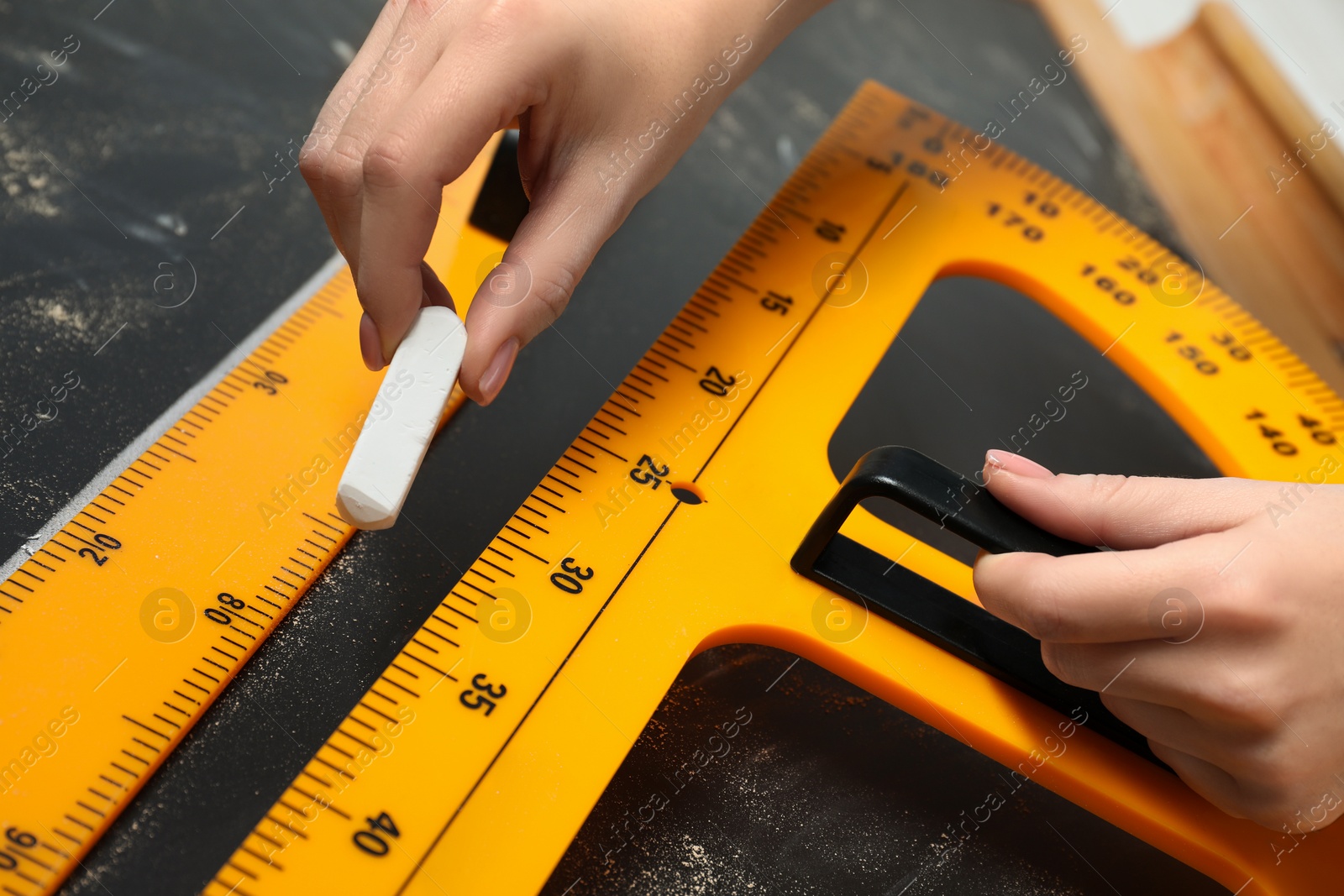 Photo of Woman drawing with chalk, ruler and protractor on blackboard, closeup
