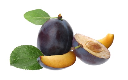 Whole and cut ripe plums with green leaves isolated on white