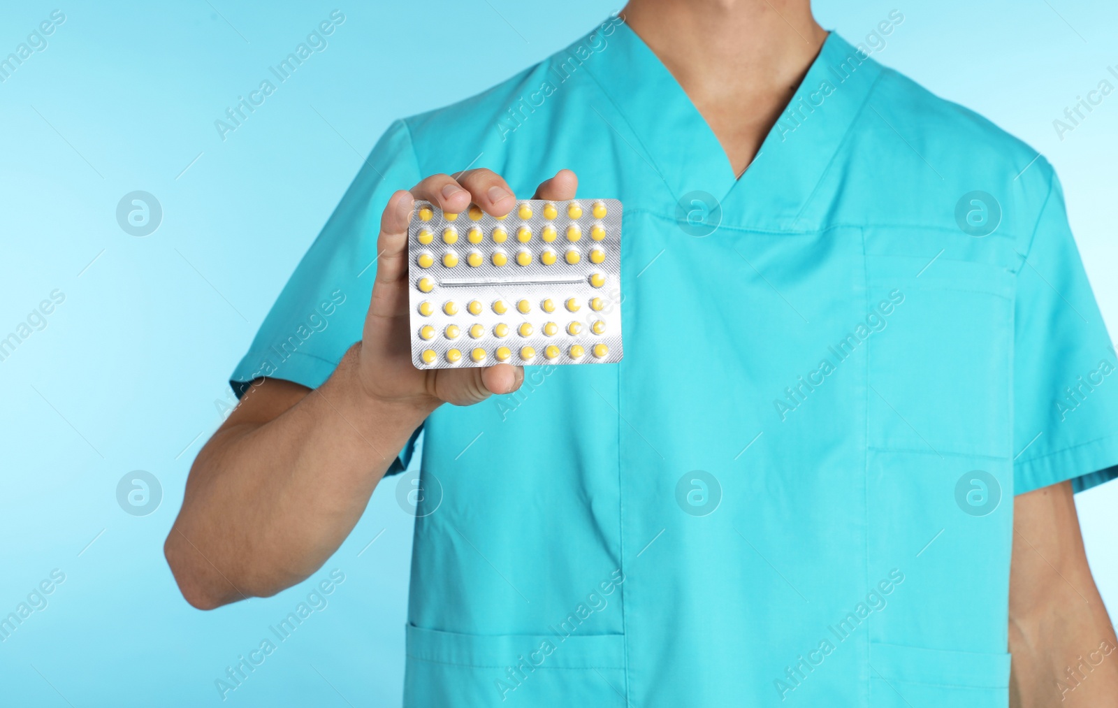 Photo of Male doctor holding pills on color background, closeup. Medical object