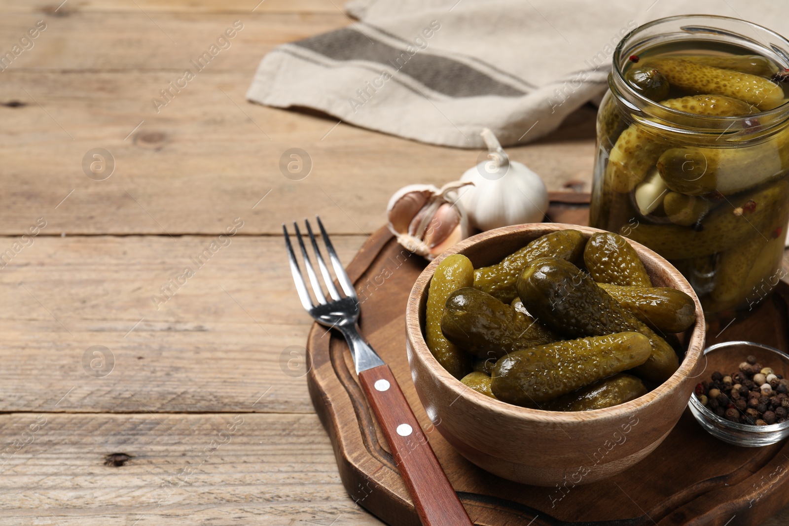 Photo of Tasty pickled cucumbers and spices on wooden table. Space for text