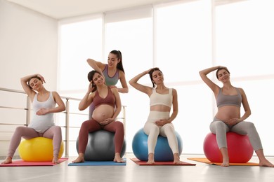 Photo of Trainer working with group of pregnant women in gym. Preparation for child birth