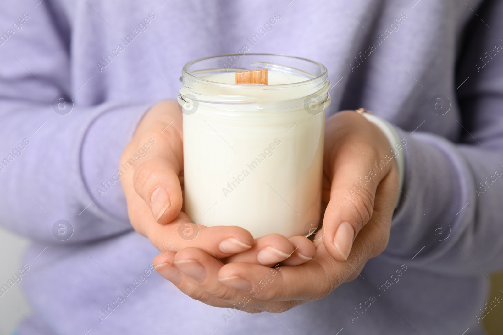 Photo of Woman holding candle with wooden wick, closeup