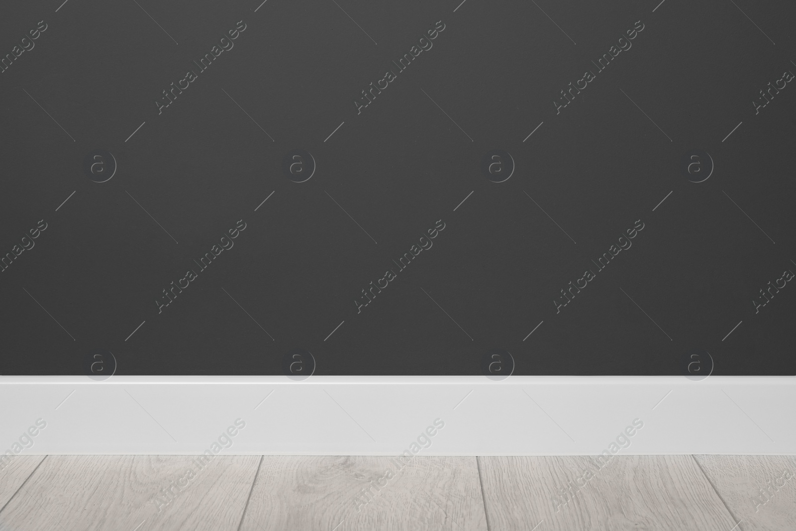 Photo of White plinth on laminated floor near black wall indoors