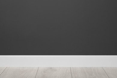 White plinth on laminated floor near black wall indoors