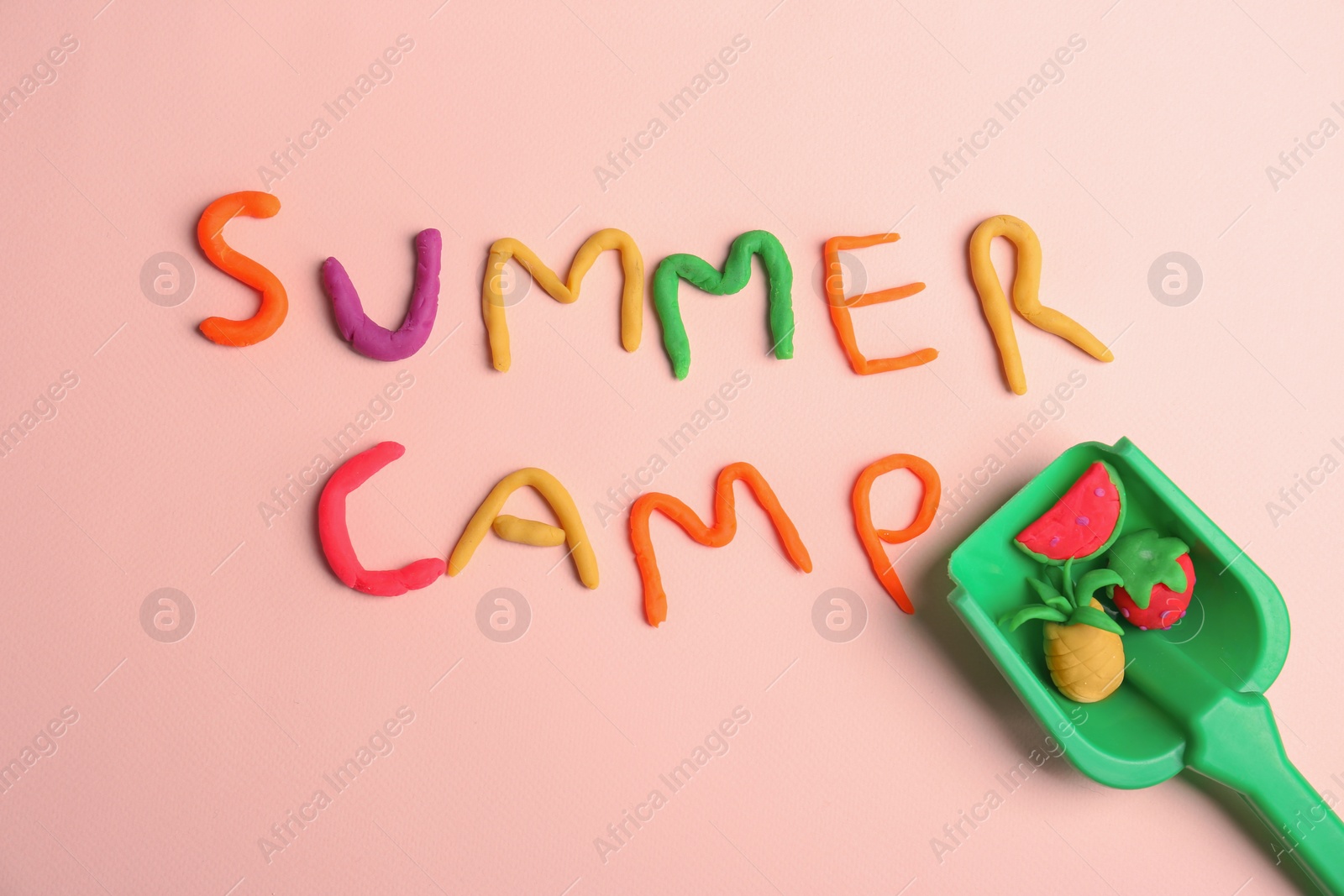 Photo of Flat lay composition with words SUMMER CAMP made from modelling clay and plastic shovel on color background