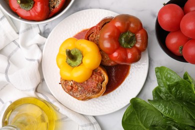 Photo of Delicious stuffed bell peppers served on white marble table, flat lay