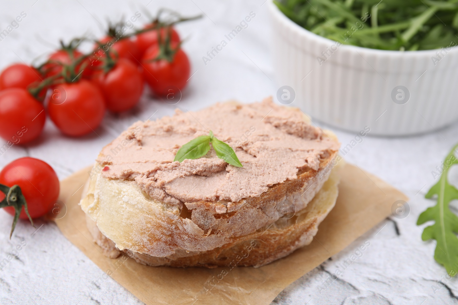 Photo of Delicious liverwurst sandwich with basil on white textured table, closeup