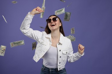 Photo of Happy woman under money shower on purple background