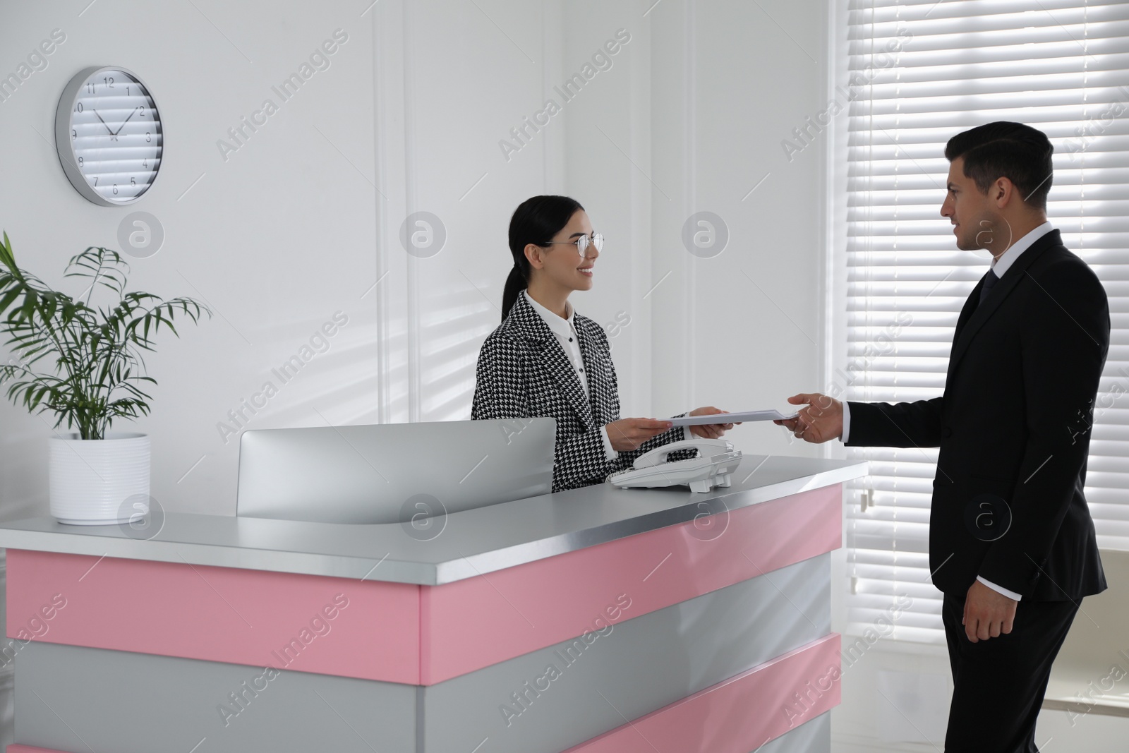 Photo of Receptionist working with client at countertop in office