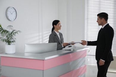 Receptionist working with client at countertop in office