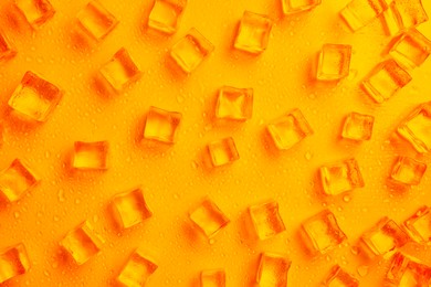 Image of Cold ice and water drops on orange background, flat lay. Ingredient for refreshing drink