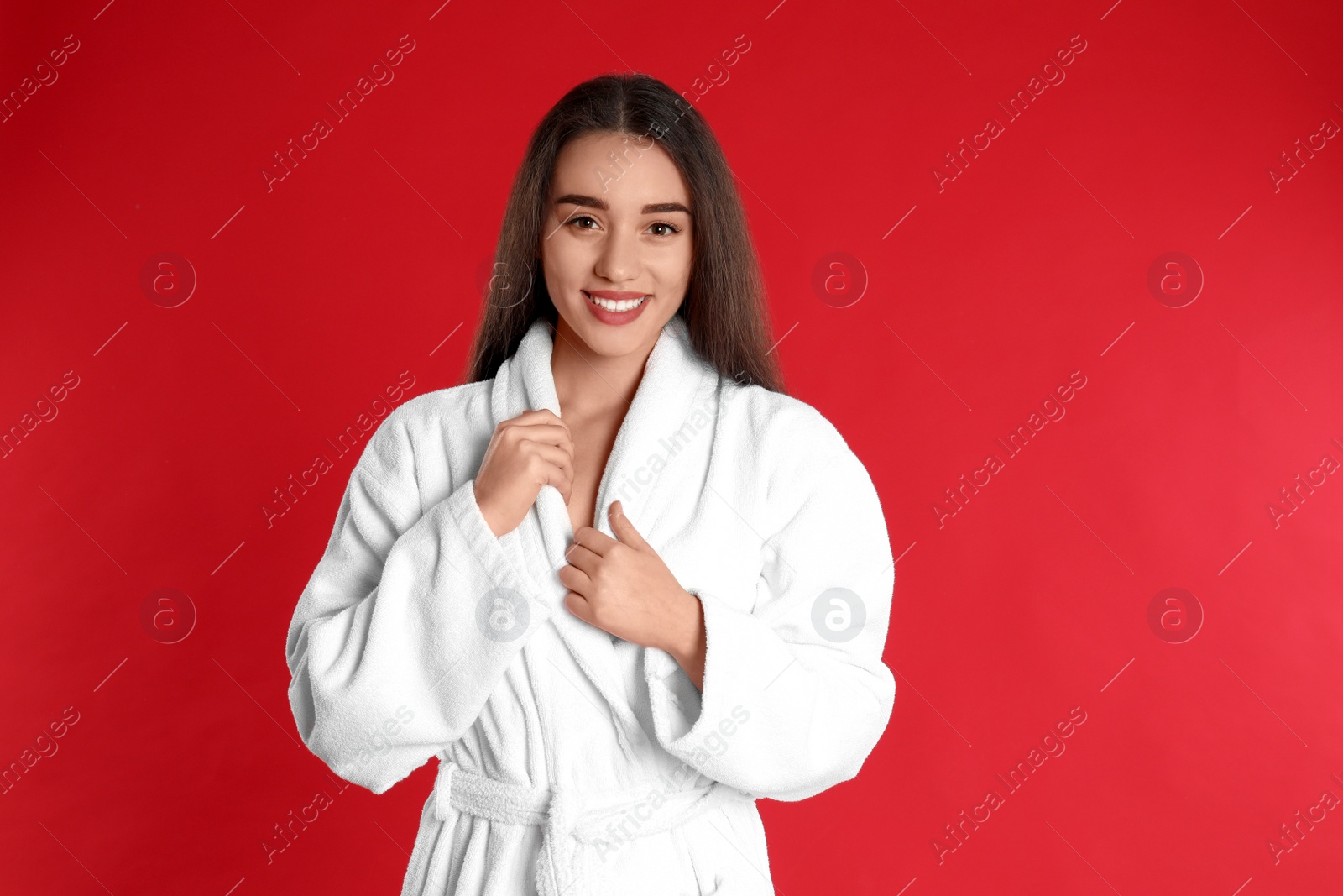 Photo of Beautiful young woman in bathrobe on red background