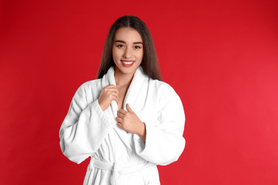 Photo of Beautiful young woman in bathrobe on red background