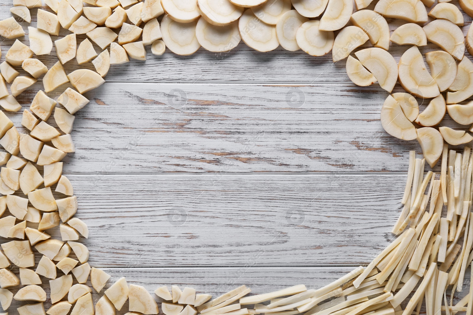 Photo of Frame of cut fresh ripe parsnips on white wooden table, flat lay. Space for text