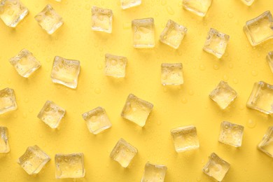 Crystal clear ice cubes on yellow background, flat lay