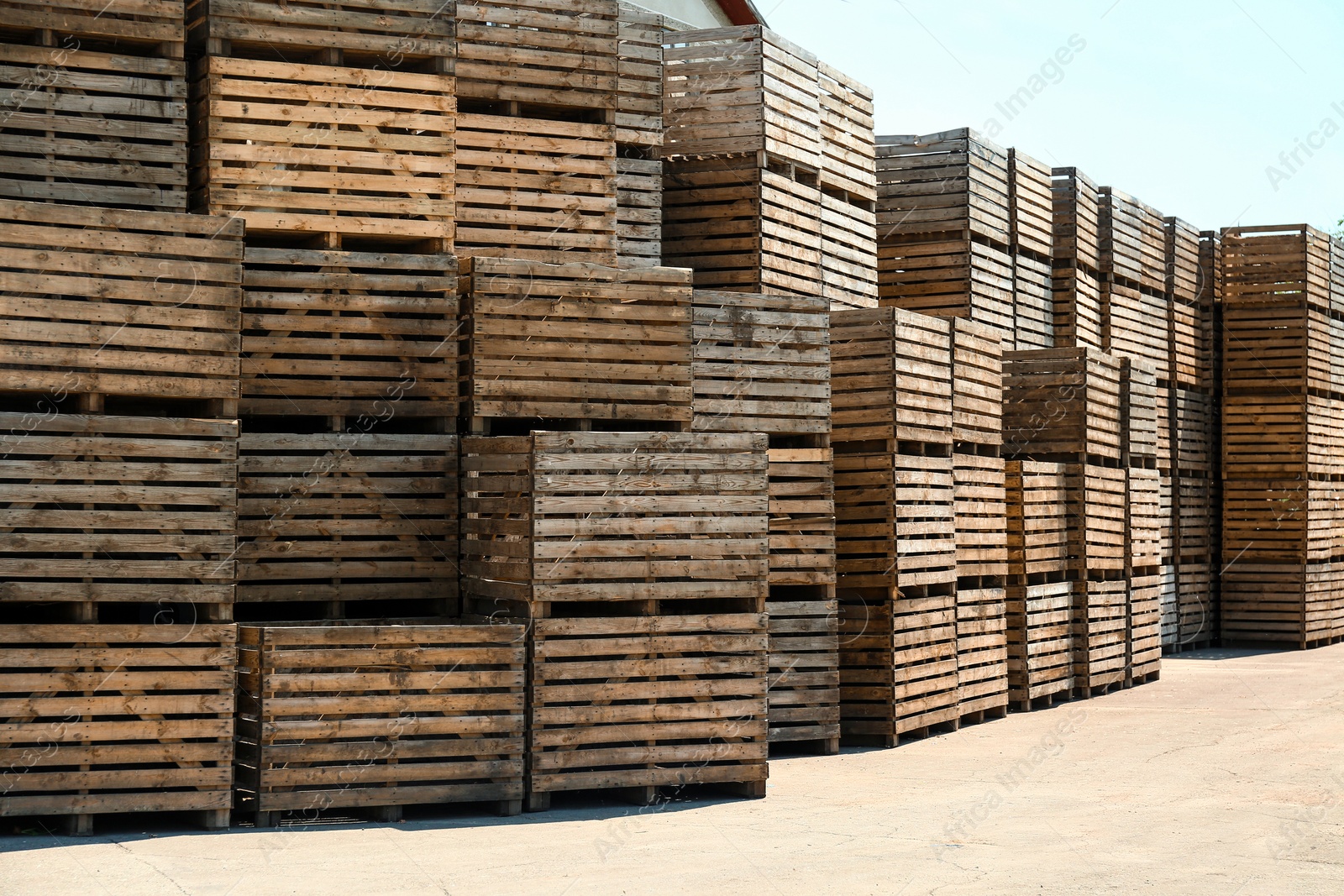 Photo of Pile of empty wooden crates outdoors on sunny day. Space for text