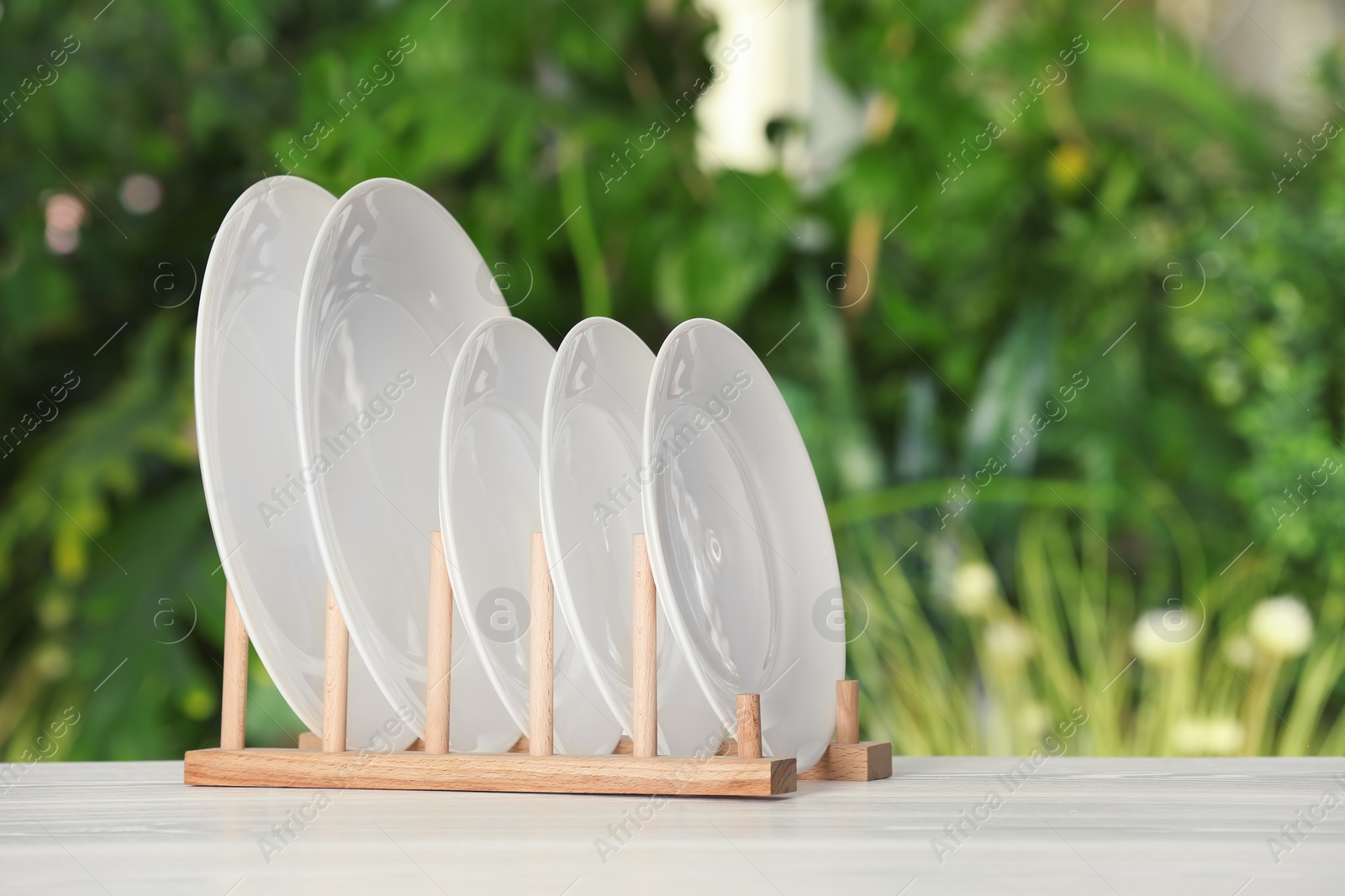 Photo of Drying rack with clean dishes on table against blurred background