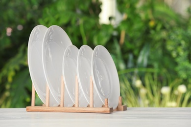 Drying rack with clean dishes on table against blurred background