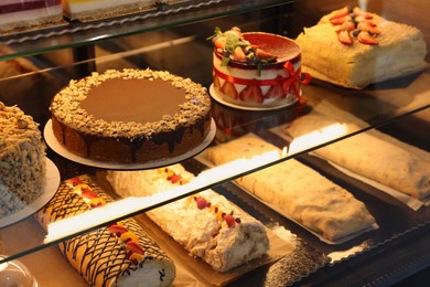 Photo of Different tasty desserts on counter in bakery shop, closeup