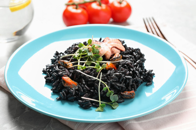 Photo of Delicious black risotto with seafood on marble table, closeup