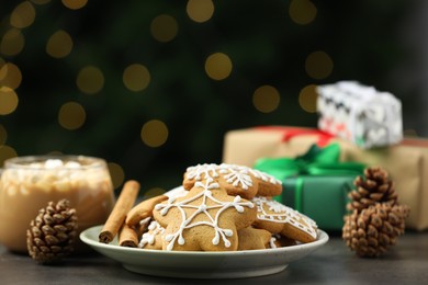 Decorated cookies and hot drink on grey table against blurred Christmas lights