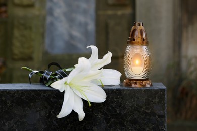Photo of White lilies and grave lantern on tombstone in cemetery
