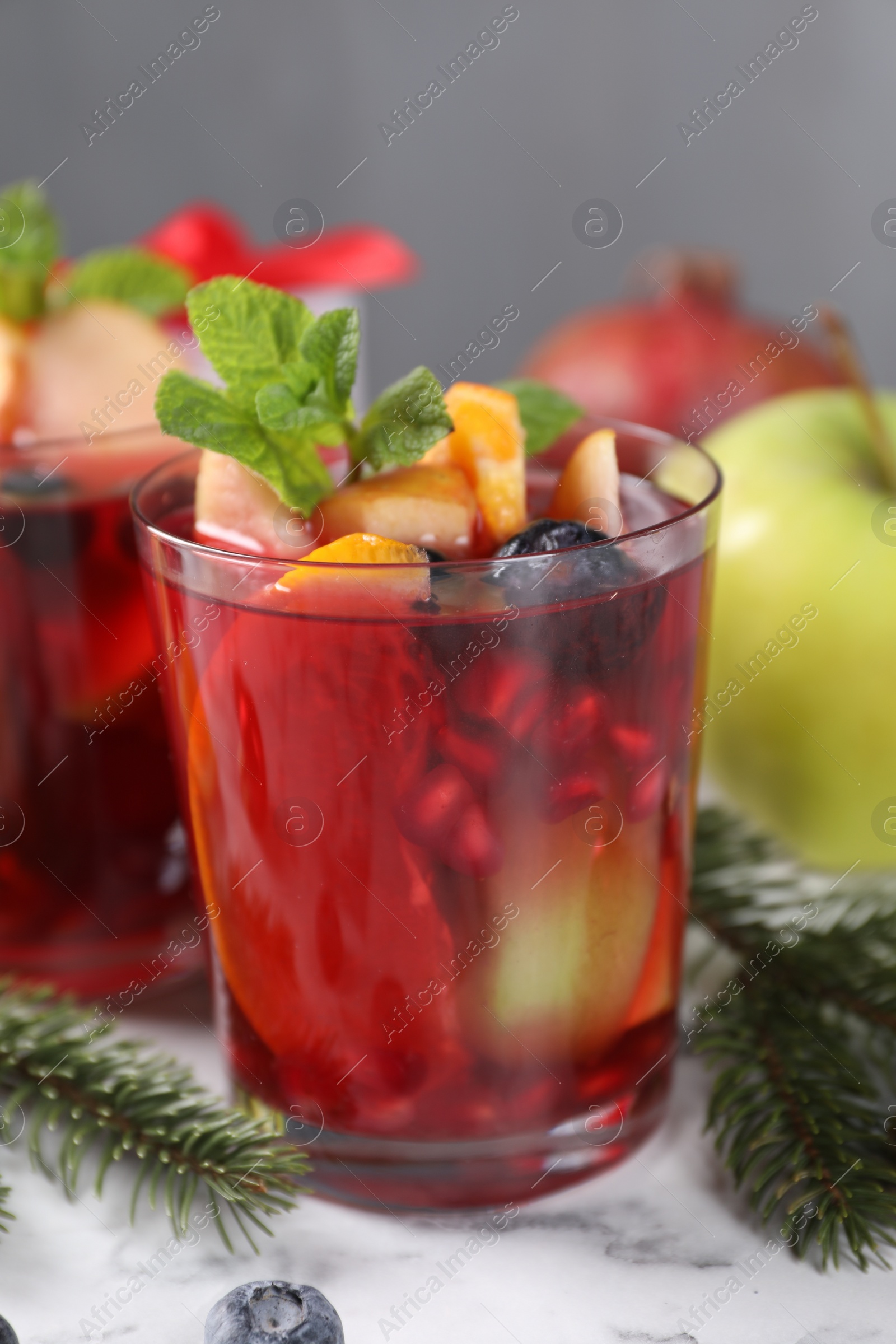 Photo of Aromatic Sangria drink in glasses, ingredients and Christmas decor on white marble table